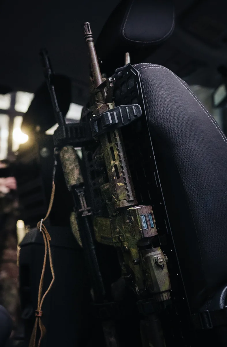 Гвинтівка AR вертикально зафіксована на сталевій MOLLE панелі на спинці сидіння в салоні авто